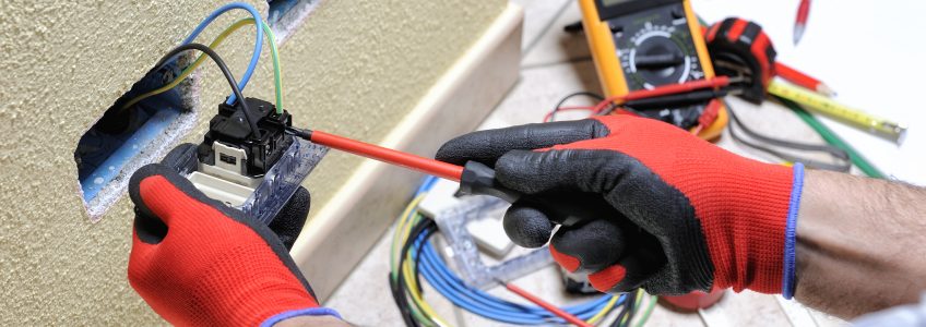 Electrician technician at work blocks the cable between the clamps of a socket in a residential electrical installation